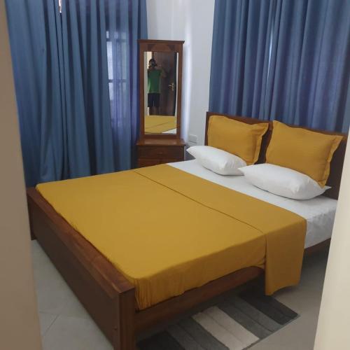 a bedroom with a bed with blue curtains and a mirror at Home stay with nuwan in Bentota