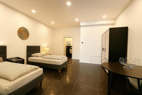 une chambre avec deux lits, une table et un bureau dans l'établissement Werre Apartments mit Smart-TV - stilvol, zentral & wohnlich, à Löhne