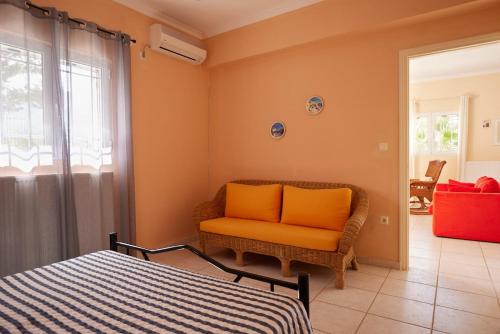 an orange chair in a room with a bed at Cozy Flat near Kato Samiko Beach in Káto Samikón