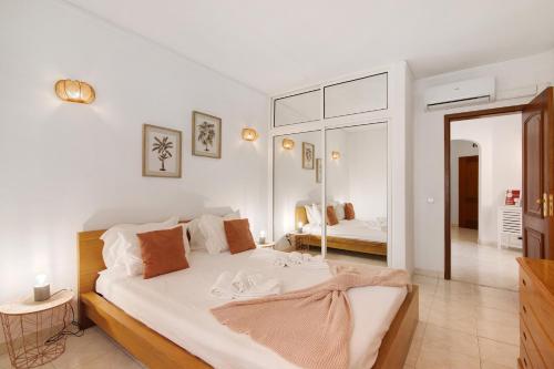 Un dormitorio blanco con una cama grande y un espejo. en Casa Abelha, en Armação de Pêra
