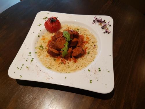 a plate of rice with meat and a strawberry on it at Logis Hôtel du Large in Plougonvelin
