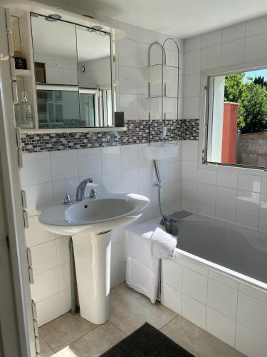 une salle de bain blanche avec un lavabo et une baignoire dans l'établissement Maison - villa avec piscine proche commerce et transports en commun, à Couëron