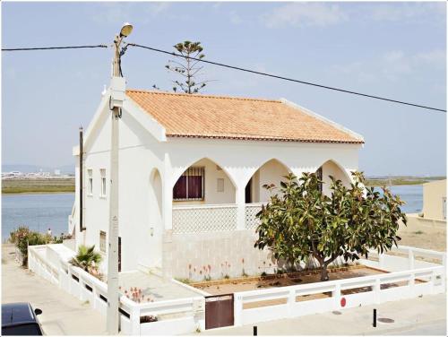 a white church with a white fence and a building at Lazaro Beach House in Faro