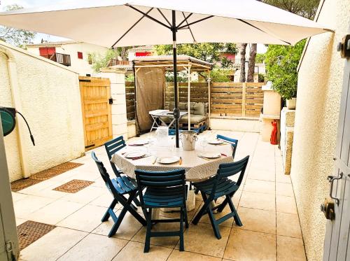 une table avec des chaises et un parasol sur une terrasse dans l'établissement Villa Sous les Pins, au Cap d'Agde