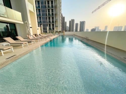 a swimming pool in a building with lounge chairs at Brand New Studio In Tulip JVC in Dubai