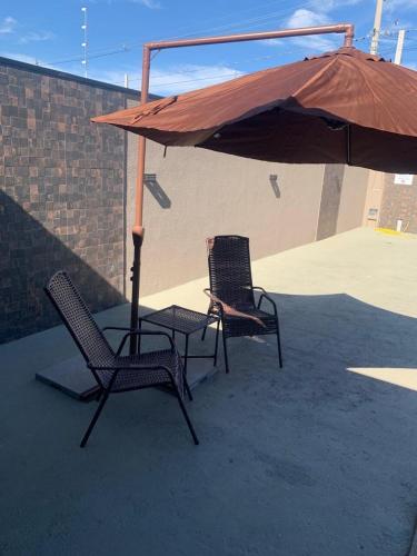 two chairs and an umbrella on a patio at Space Mistieri in Espirito Santo Do Pinhal