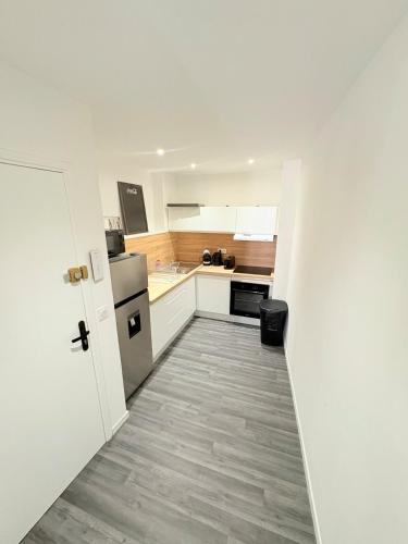 une petite cuisine avec des placards blancs et un couloir dans l'établissement 3P Cozy Movie Room Historic Heart of Clermont, à Clermont-lʼHérault