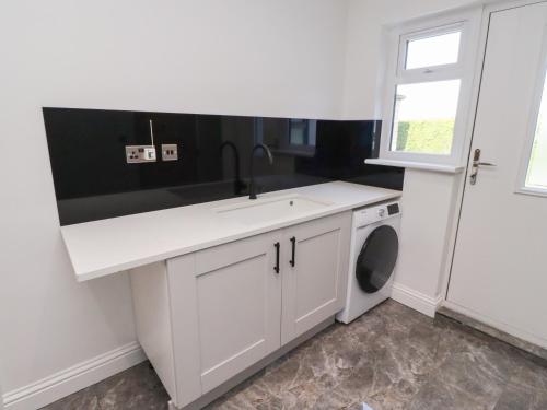 une cuisine blanche avec un évier et une machine à laver dans l'établissement Rose Cottage, à Alnwick