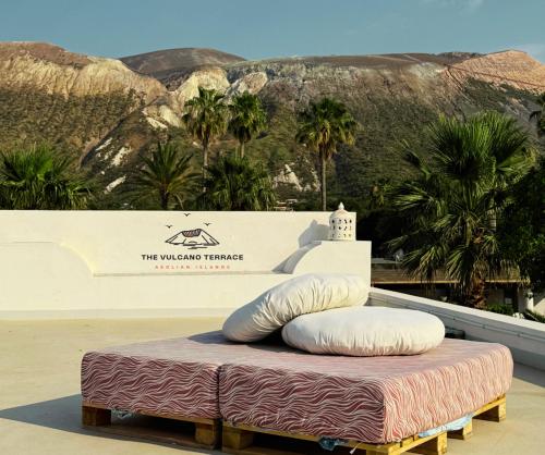 a bed with pillows on top of it with a mountain at The Vulcano Terrace in Vulcano