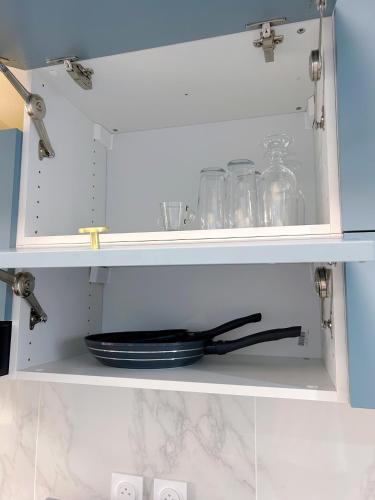 une armoire blanche avec une assiette et des bocaux en verre dans l'établissement Hébergement design proche plage, à Trouville-sur-Mer