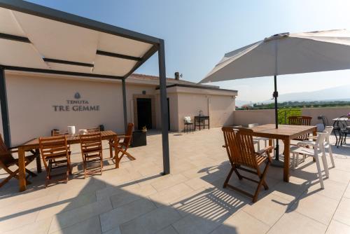 a patio with tables and chairs and an umbrella at Tenuta Tre Gemme in Cantina- Renascenzia SantIrene in Catignano