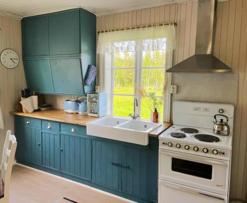 a kitchen with blue cabinets and a sink and a stove at Idyllisk Småbruk in Landsem