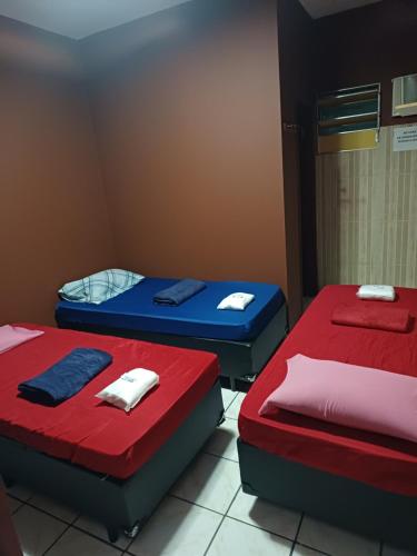 three beds in a room with red and blue at Hotel coruja's, Santo amaro ,São Paulo-SP in São Paulo