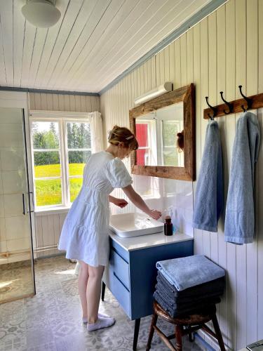 a woman standing at a sink in a bathroom at Idyllisk Småbruk in Landsem