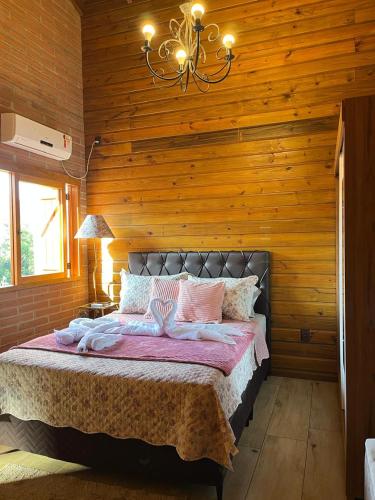 ein Schlafzimmer mit einem Bett in einer Holzwand in der Unterkunft Cabana Bela Vista in Santa Maria do Erval