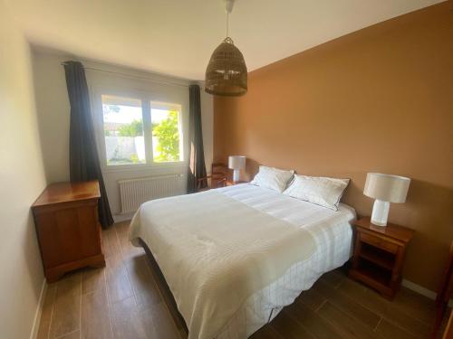 une chambre avec un lit blanc et une fenêtre dans l'établissement Le Frangipanier, à Les Sables-dʼOlonne