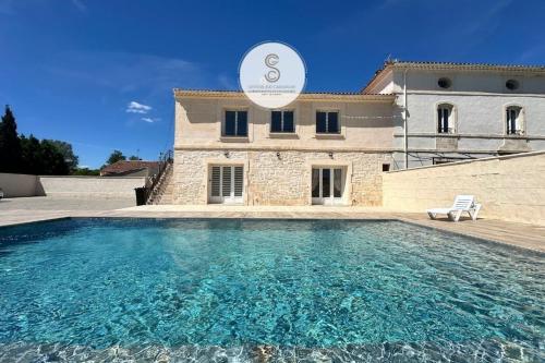 une grande piscine devant une maison dans l'établissement L'Eau Bleu Arles, à Arles