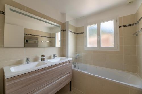 een badkamer met een wastafel, een bad en een spiegel bij Lagrange Vacances - Eden Parc Golf in Lacanau-Océan
