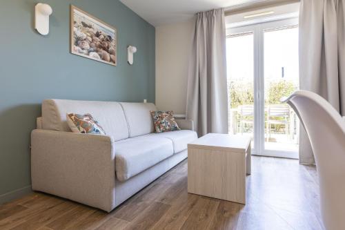 a living room with a couch and a table at Résidence Odalys Les Villas de la Baie in Le Crotoy