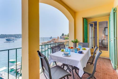 une table sur un balcon avec vue sur l'eau dans l'établissement EDEN VIEW AP4469 by Riviera Holiday Homes, à Villefranche-sur-Mer