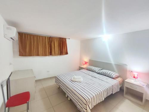 a small bedroom with a bed and a red chair at Mamma Casa City Center Lampone in Rimini