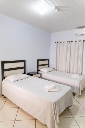 two beds in a room with white walls at Hotel Village in Pato Branco