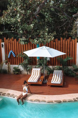 a woman sitting in a swimming pool with an umbrella and chairs at Kalimera Beach Hotel in Maya Beach