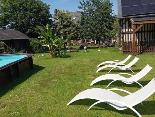 a group of white chairs sitting in the grass next to a pool at La Gerbaudiere Chambres&Table d hotes proche Mont Saint Michel CUISINE MAISON in Notre-Dame-du-Touchet