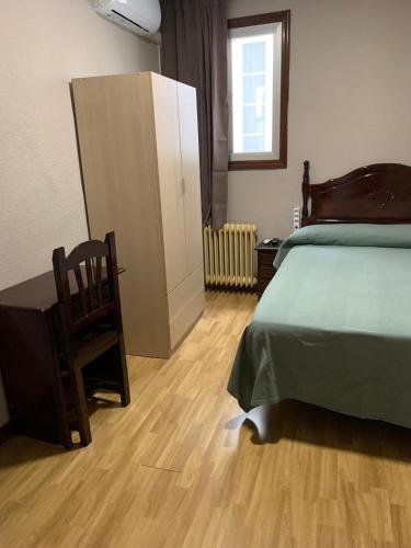 a bedroom with a bed and a desk and a chair at Hostal Río Paraná in Madrid