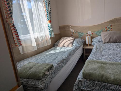 two beds in a small room with a window at Abi static caravan close to Edinburgh in Port Seton