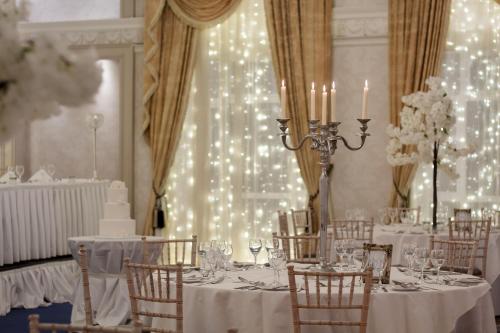 a dining room with white tables and chairs and lights at The Newgrange Hotel in Navan