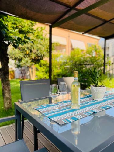 a table with two glasses and a bottle of wine at Casa Piero, relax e piscina privata tra le colline delle Langhe in Alba