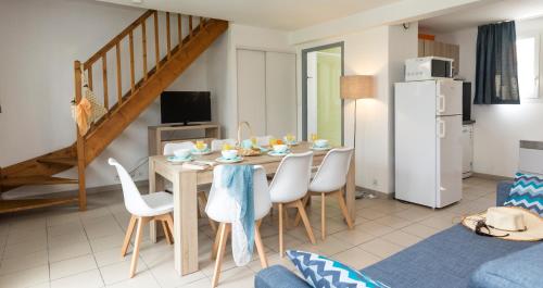 a kitchen and dining room with a table and chairs at Résidence Odalys Le Village des Amareyeurs in Le Château-dʼOléron