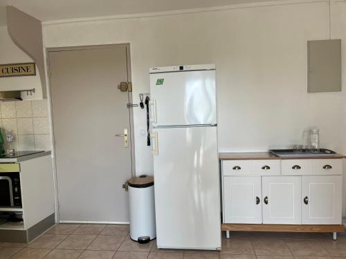- un réfrigérateur blanc dans une cuisine à côté d'une porte dans l'établissement Appt BORD DE MER MARSEILLAN PLAGE, à Marseillan
