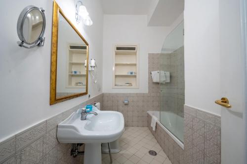 a bathroom with a sink and a mirror and a tub at Hotel Belvedere in Conca dei Marini