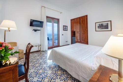 a bedroom with a bed and a table with a lamp at Hotel Belvedere in Conca dei Marini