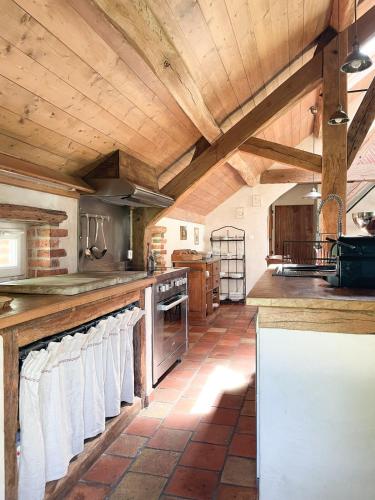eine große Küche mit Holzdecken und weißen Handtüchern in der Unterkunft Maison avec piscine & tennis partagés - proche Châteaux de la Loire - 1h30 de Paris in Combreux