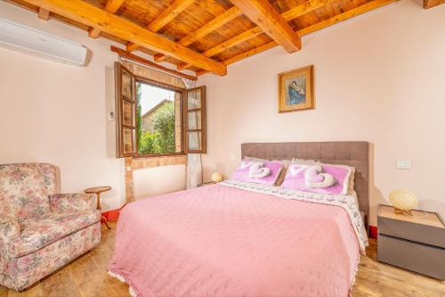 a bedroom with a pink bed and a chair at B&B Al Vecchio Forno in Montepulciano