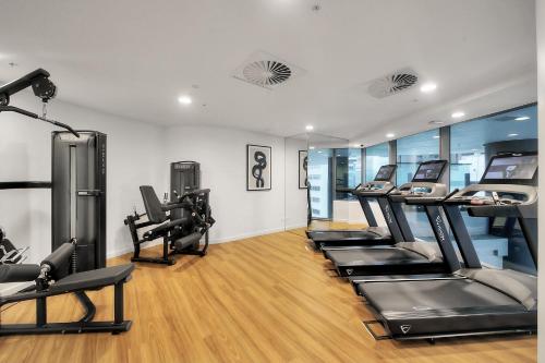 a gym with treadmills and elliptical machines at River Glow at Queens Wharf Level 43 in Brisbane