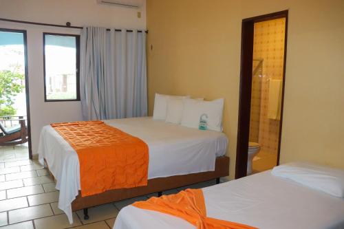 a hotel room with two beds and a balcony at Pousada Vivenda Oriente in São José da Coroa Grande