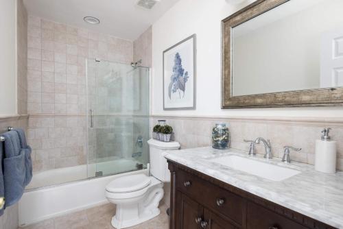 a bathroom with a toilet and a sink and a mirror at Dunecrest by RoveTravel - Family Oceanfront with Heated Pool in Westhampton Beach