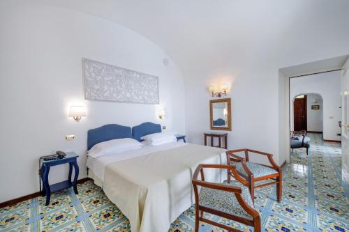 a hotel room with a bed and two chairs at Hotel Belvedere in Conca dei Marini