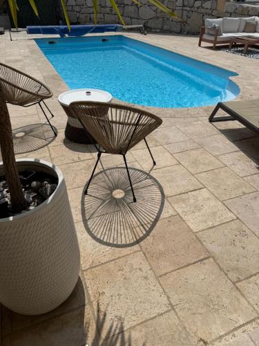 une piscine avec une table et une chaise à côté d'une piscine dans l'établissement Bas de Villa à 15 min de Nice avec piscine, à Carros