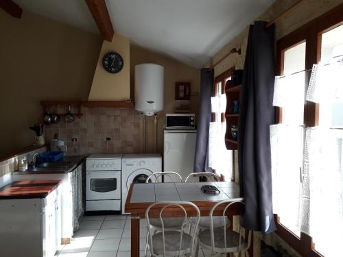 - une cuisine avec des appareils blancs, une table et des chaises dans l'établissement Appartement , rue piétonne , centre village, à Nissan-lez-Enserune
