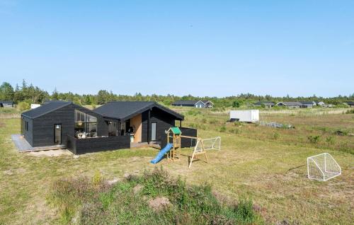 a black house with a playground in a field at Nice Home In Jerup With Sauna in Jerup