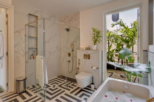 La salle de bains est pourvue d'une douche, de toilettes et d'une baignoire. dans l'établissement Summerville · Luxurious 3bhk villa in Arpora, à Goa