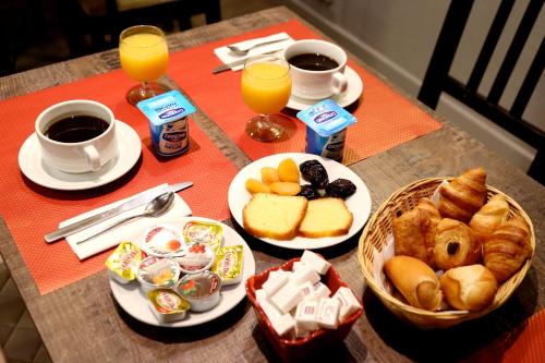 a table with plates of breakfast foods and cups of coffee at Hotel Paris Villette in Paris