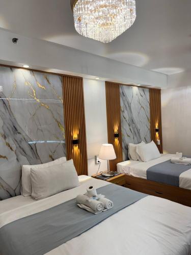 a hotel room with two beds and a chandelier at Relax in Pasay Citys Best Kept Secret - Spacious Condo with Garden View in Manila