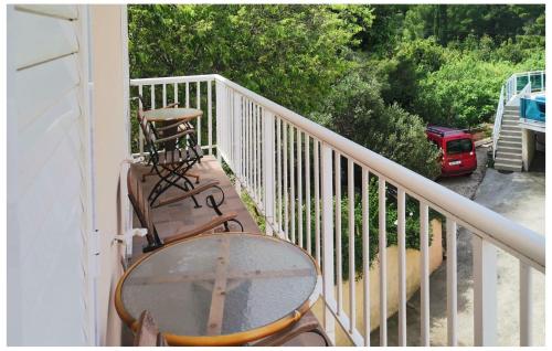 Un balcón con sillas y una mesa y un coche rojo. en Amazing Apartment In Cavtat With Wifi, en Cavtat