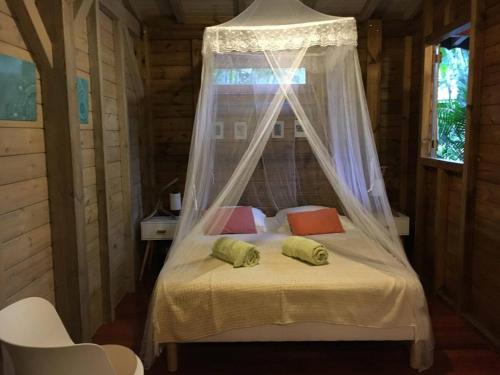a bedroom with a bed with a canopy and two pillows at Le MORNE Aux F0US Cabanes & Jardin Tropical in Deshaies